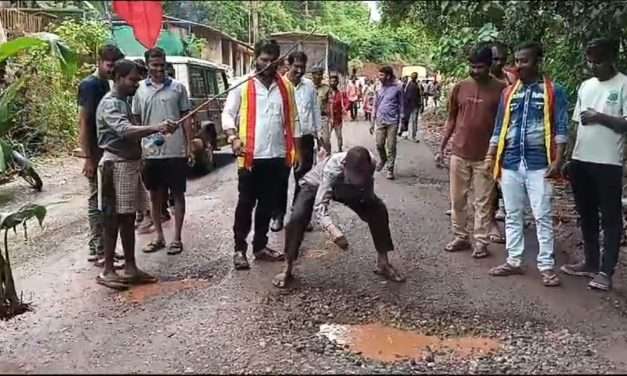 ರಸ್ತೆಯ ಹೊಂಡದಲ್ಲಿ ಅಧಿಕಾರಿಗಳಿಗೆ ಮೀನು ತೋರಿಸಿದ  ಪ್ರತಿಭಟನಾಕಾರರು.